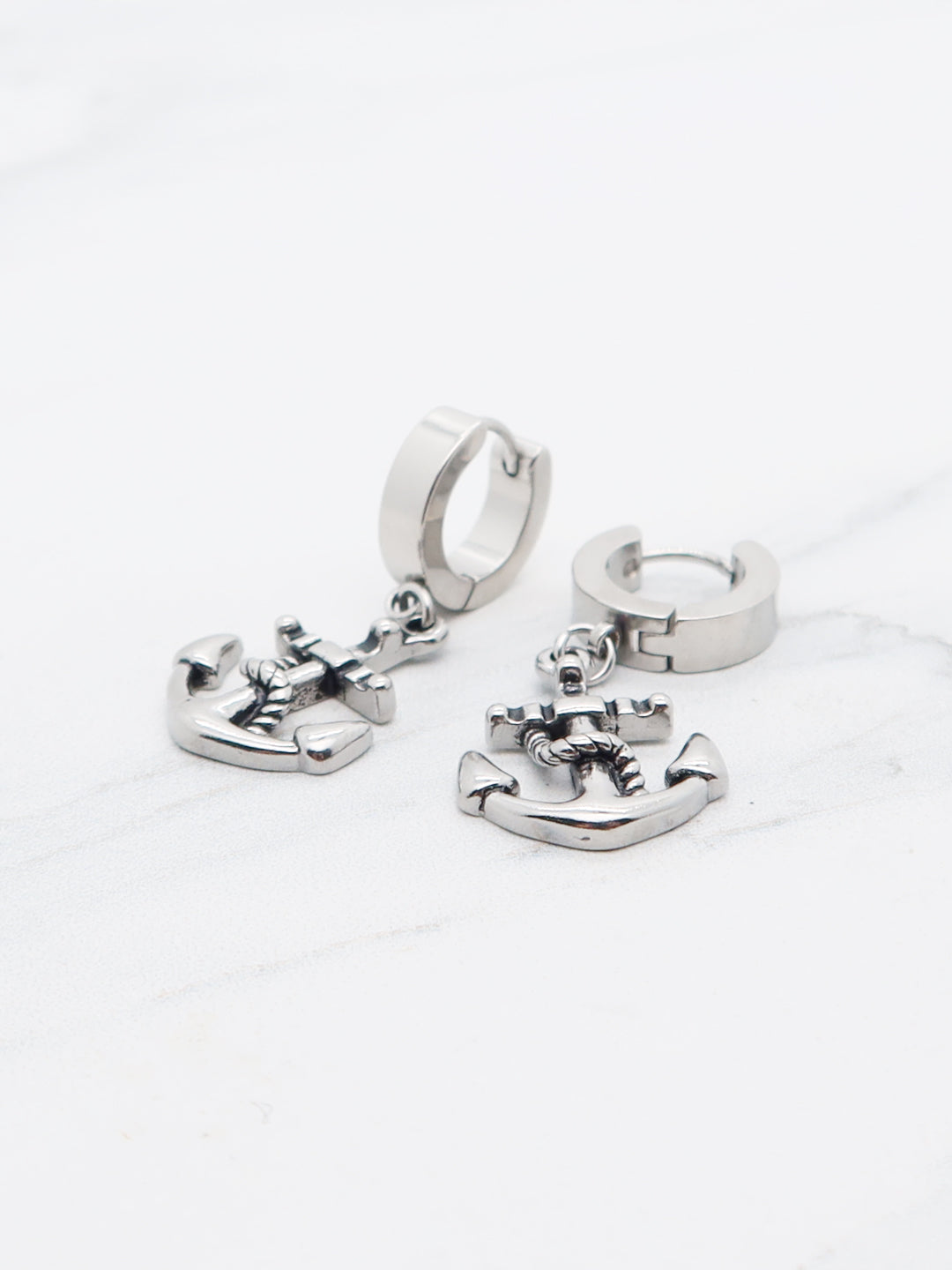 Titanium anchor dangle earrings on marble background