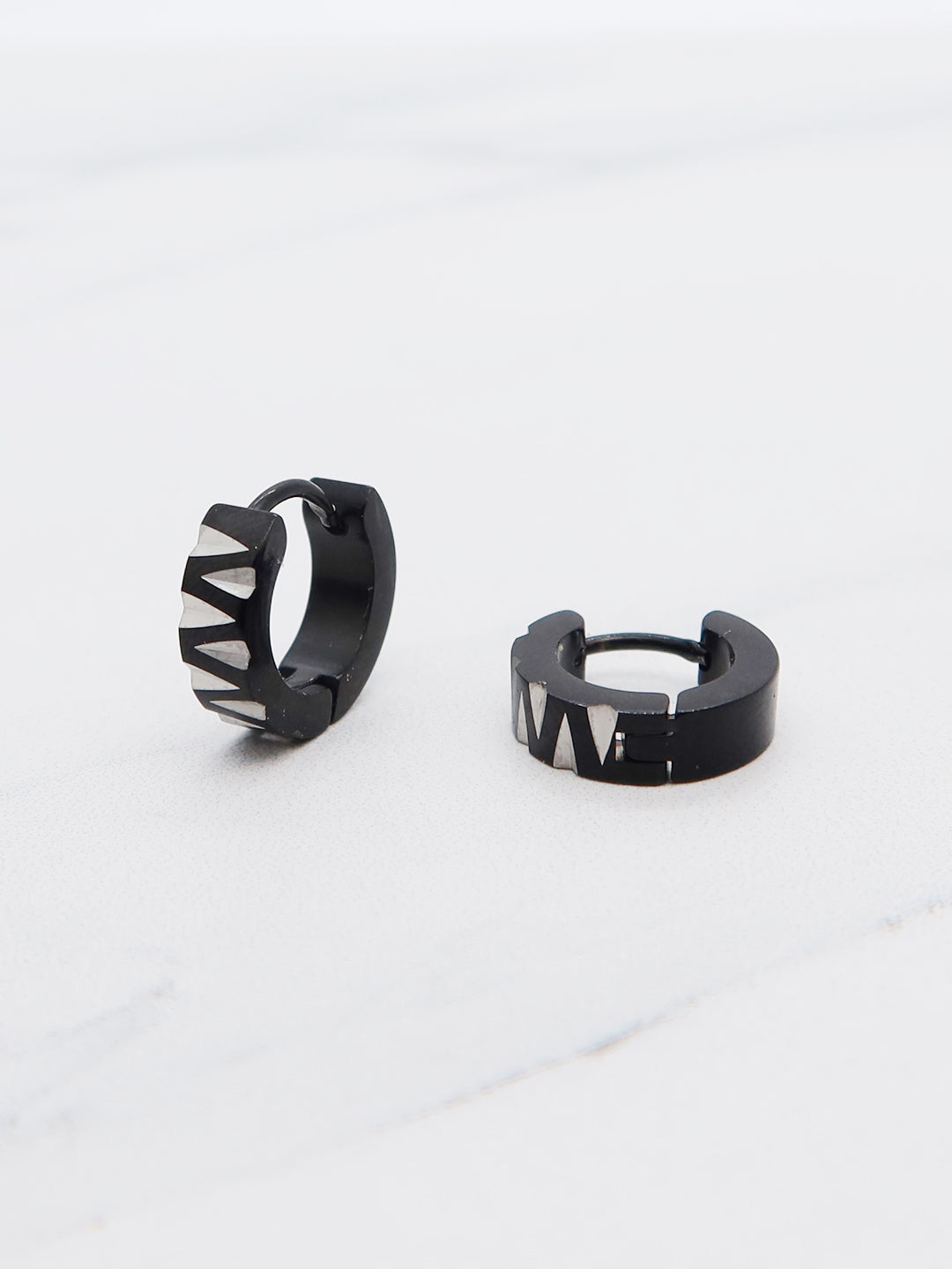 Black and silver titanium hoop earrings featuring a bold triangle pattern in huggie-style design