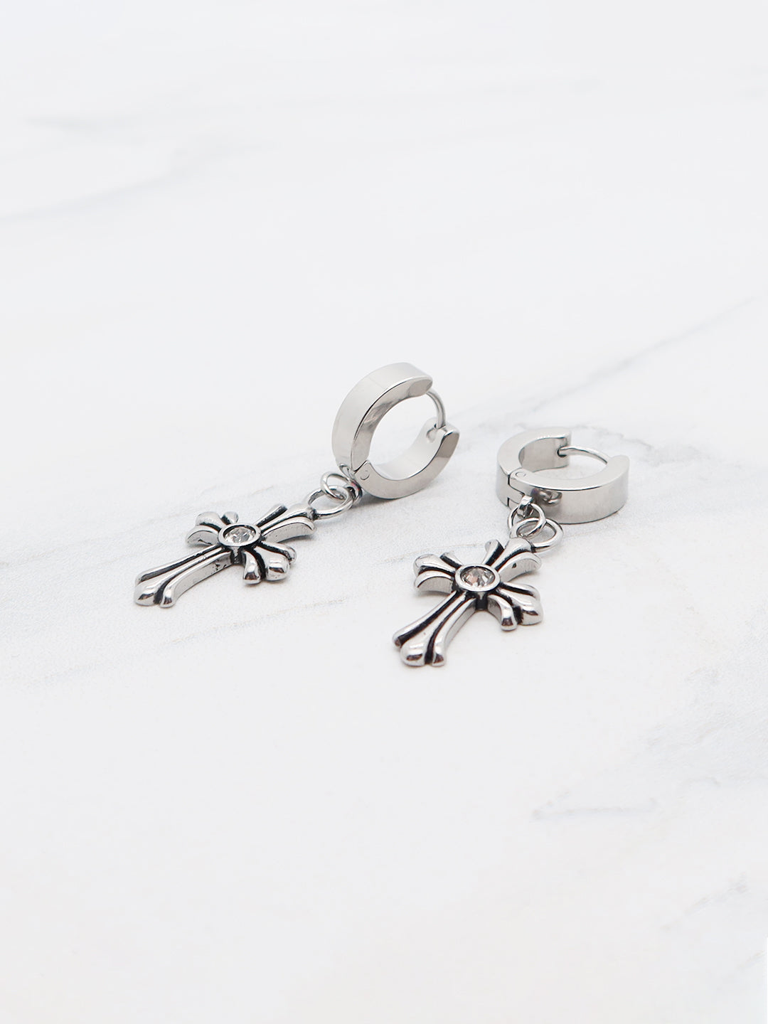 Titanium cross dangle hoop earrings with a sleek charm, displayed on a white background.