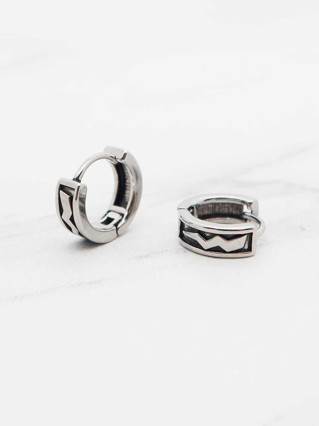 Titanium huggie hoops with black chevron pattern.
