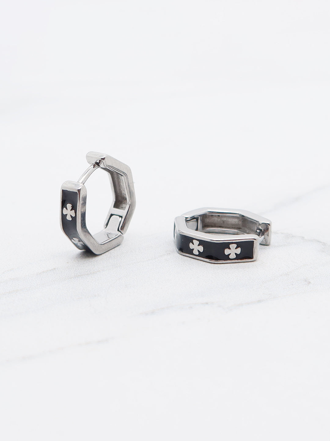 Hexagonal titanium huggie hoops with black enamel and clover details.