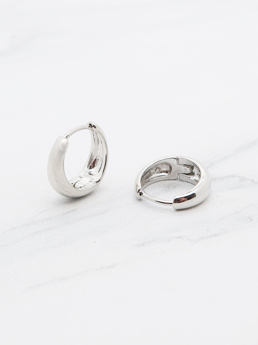 Sleek titanium huggie hoops with a polished finish.