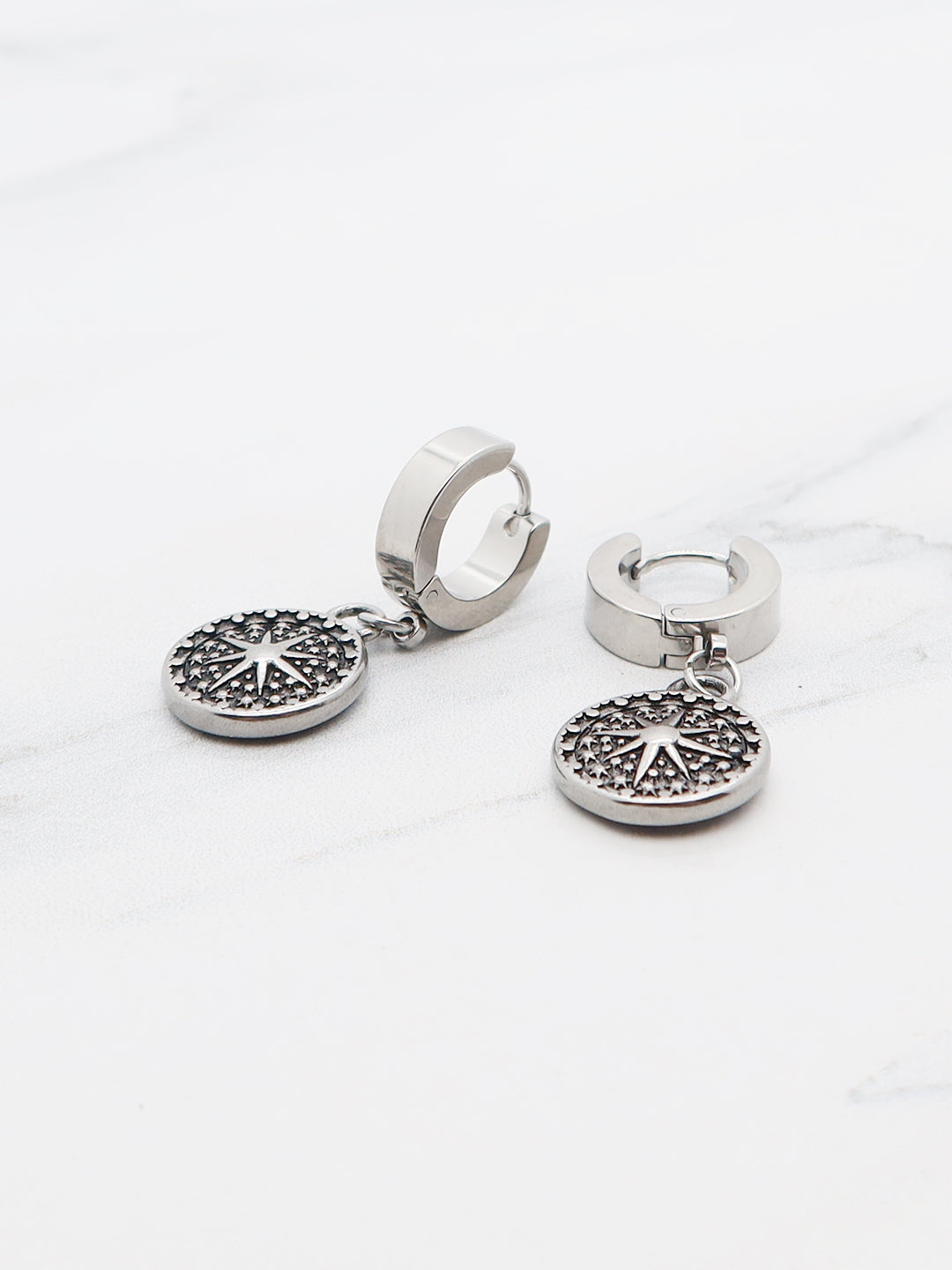 Titanium huggie earrings with a star sigil medallion, gothic celestial jewelry.