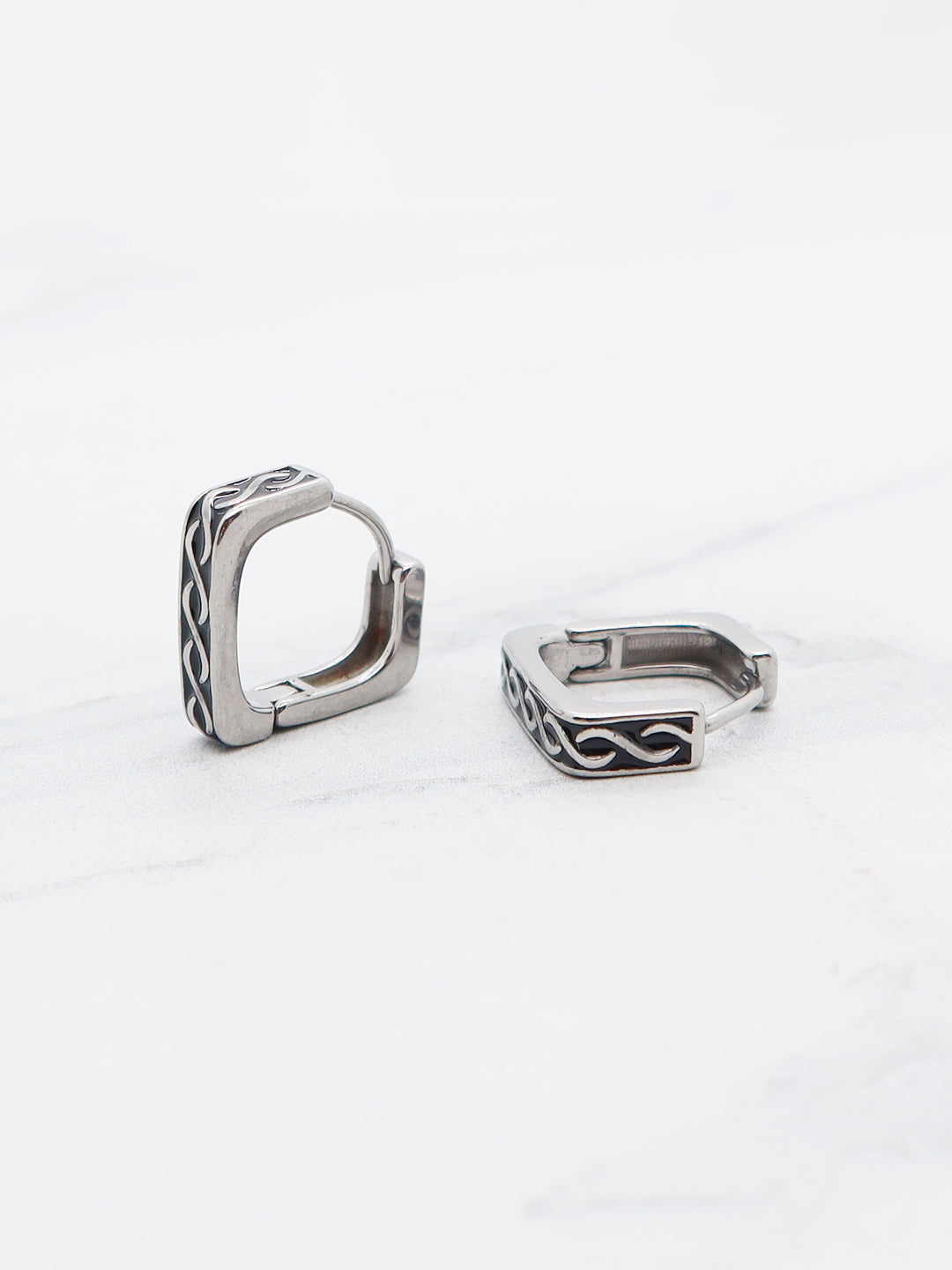 Titanium square hoop earrings featuring an engraved tribal pattern, displayed on a white background.