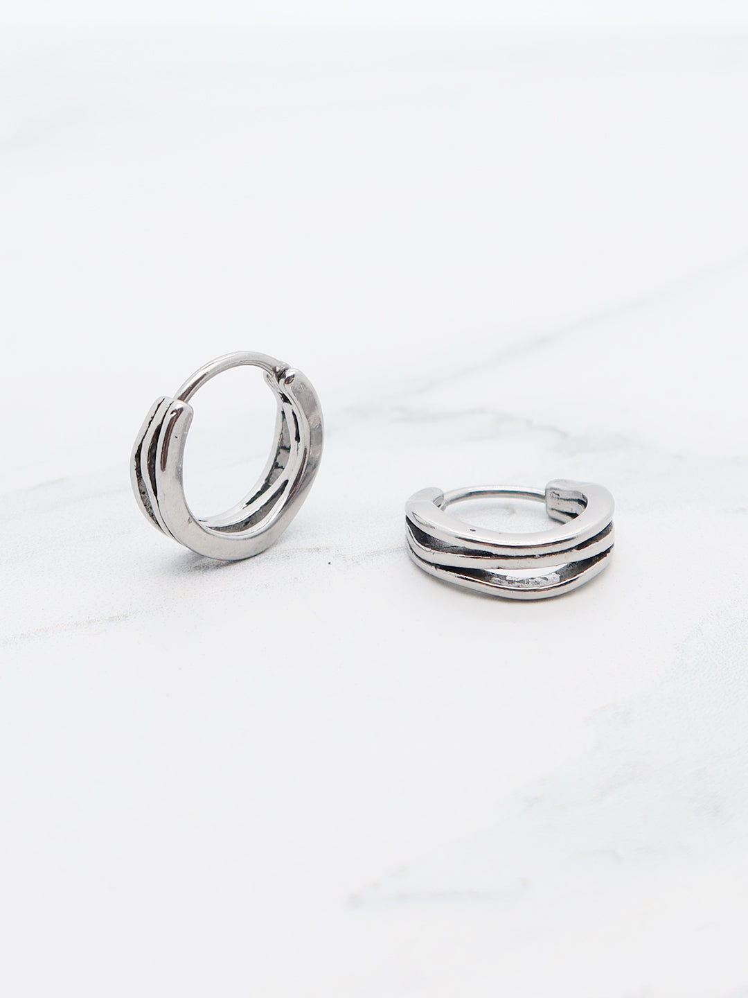 Wavy hoop earring in stainless steel with textured grooves.