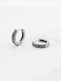 Close-up view of daisy-patterned hoop earrings with hinged clasp
