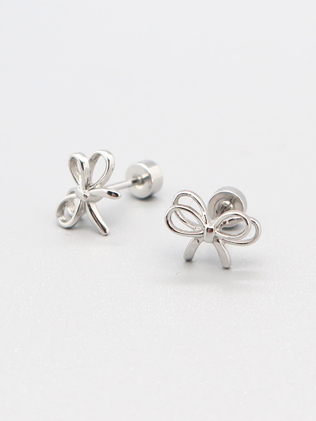 Delicate silver bow stud earrings with screw-back closure for sensitive ears.